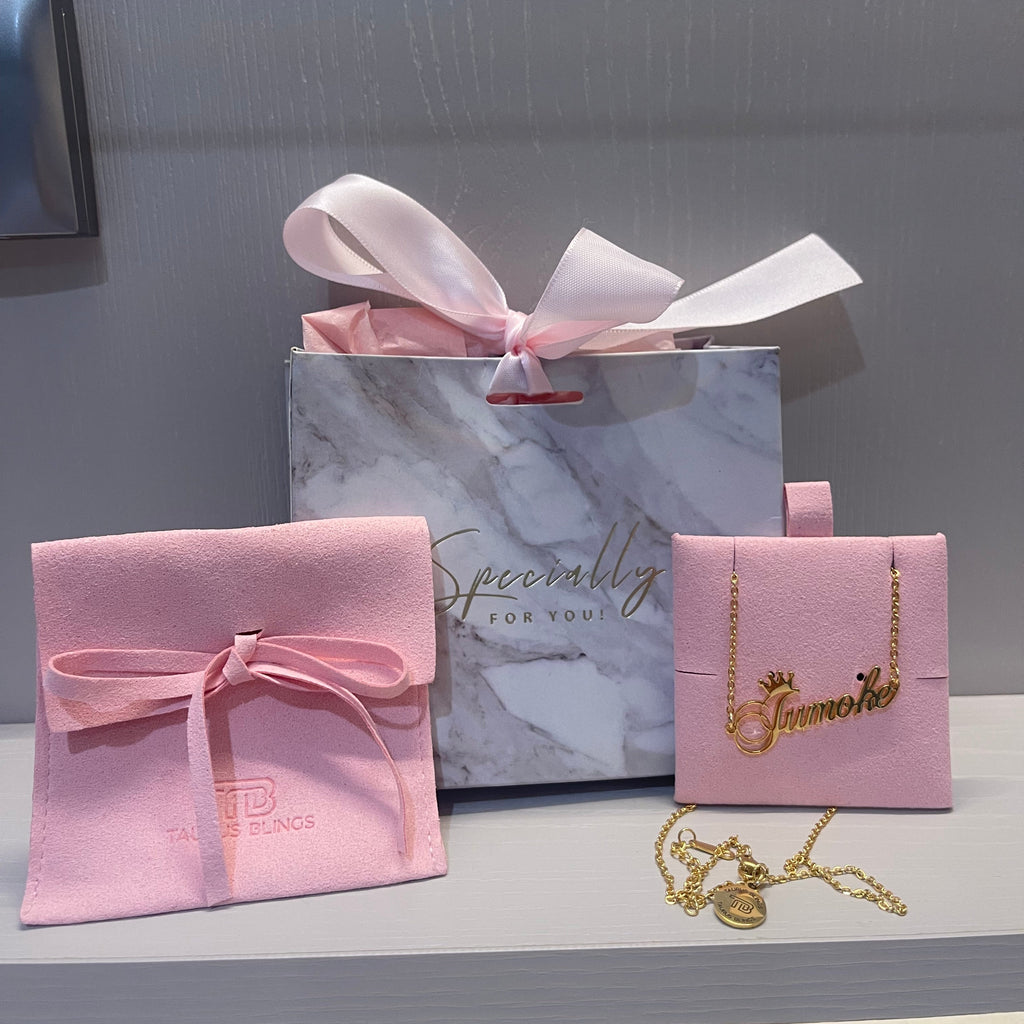 Pink gift box with a bow and jewelry on a gray surface